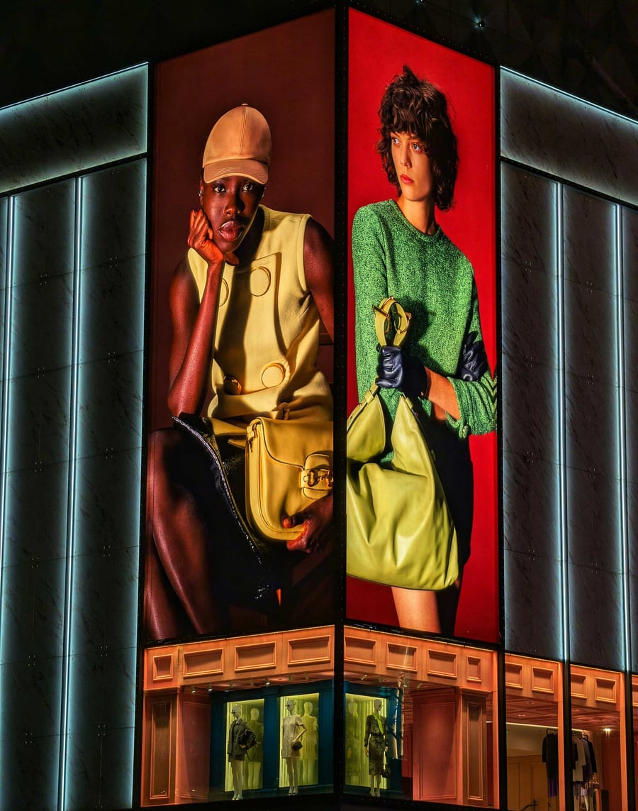 Illuminated fashion campaign posters on a store facade at night