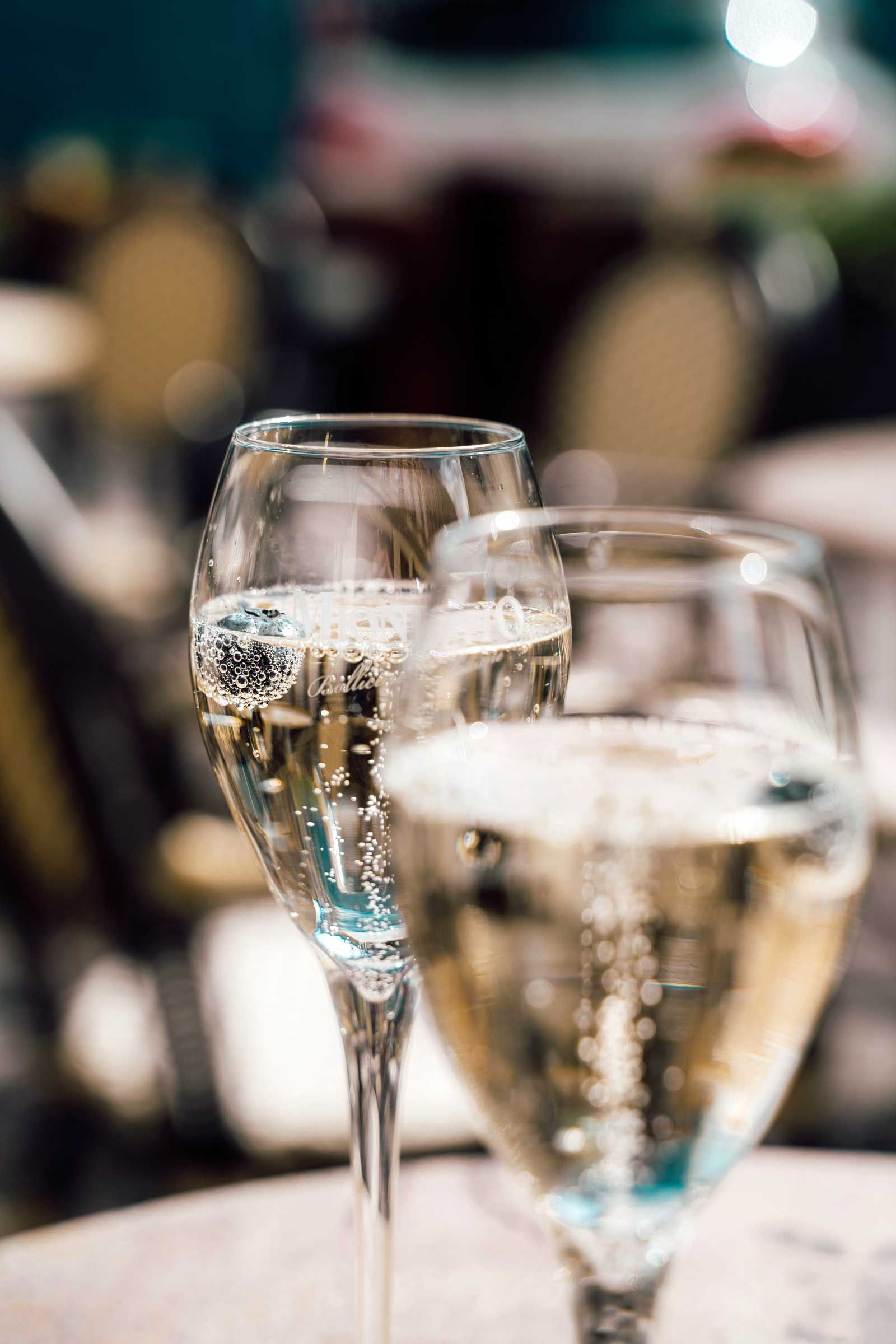 Two glasses of a sparkling drink on a sunlit cafe table